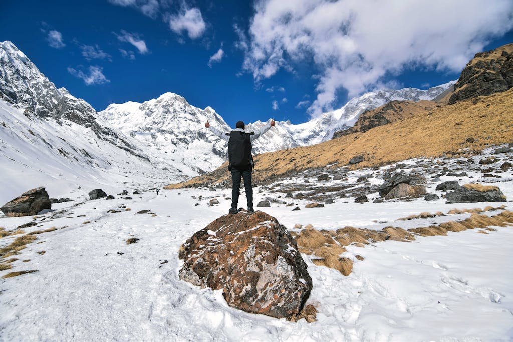 An inspiring view of a hiker with arms raised, surrounded by the snow-capped peaks of Jomsom, Nepal.